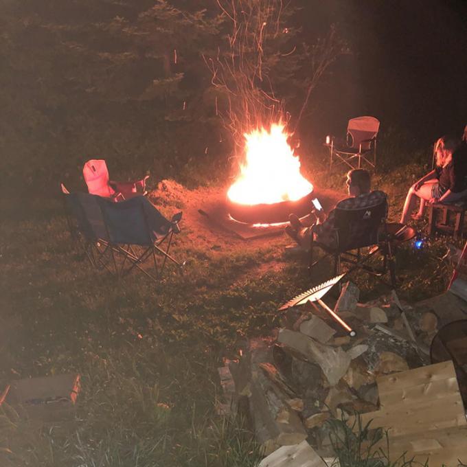 Κήπος κοιλωμάτων πυρκαγιάς χάλυβα γύρω από το ξύλο κύπελλων πυρκαγιάς που καίει το υπαίθριο μαύρο κοίλωμα πυρκαγιάς χρώματος χάλυβα Corten